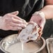 A person pouring Rich's Donut Glaze onto a doughnut.