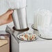 A hand holding a Choice stainless steel flatware holder filled with plastic bags.