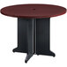 A round Bridgeport peninsula table with a black base and a cherry top.