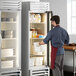 A man opening the glass door of a Beverage-Air reach-in refrigerator in a professional kitchen.