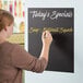 A woman writing on a Choice chalkboard roll on a counter.