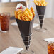 A black Carnival King cardboard cone filled with french fries.