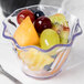 A table with a Cambro clear swirl bowl filled with fruit.