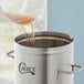 A liquid being poured into a Choice 2 Gallon Round Iced Tea Dispenser.