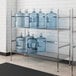 A Regency metal wire rack with two shelves holding water jugs.