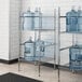 A Regency metal wire rack holding water jugs.
