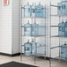 A chrome metal Regency water jug rack with three shelves holding water jugs.