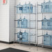A Regency chrome wire shelving unit holding water jugs.