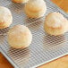 A round white bread on a Fat Daddio's stainless steel cooling rack.