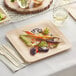 A Bamboo by EcoChoice compostable square plate with vegetables on a table.