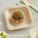 A mushroom sitting on a TreeVive by EcoChoice wooden square plate with food on it, with a fork and knife