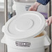 A person wearing gloves opens a white Baker's Mark ingredient bin lid.