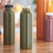 A person holding a clear round PET juice bottle next to other juice bottles on a counter.