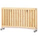 A natural wood full size folding crib with wheels.