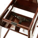 A wooden high chair with a black strap on a wooden surface.