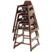 A stack of unassembled wooden high chairs with an antique cherry finish.
