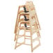 A stack of unassembled natural wood high chairs with black straps.