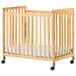 A Foundations SafetyCraft natural wood crib with a mattress on it.