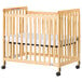 A natural wood crib with a white mattress in it.