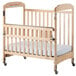 A natural wood Foundations Serenity SafeReach crib with a white sheet on the mattress.