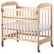 A natural wood Foundations Serenity SafeReach crib with a white sheet.