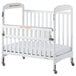 A white Foundations Serenity SafeReach compact wood crib with a white sheet on wheels.