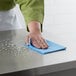 A person cleaning a surface with a blue ChoiceHD foodservice wiper.