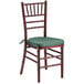 A Lancaster Table & Seating mahogany wood Chiavari chair with a green cushion.