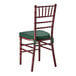 A mahogany wood Chiavari chair with a green cushion.