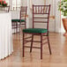 A mahogany wood Chiavari chair with a green cushion.
