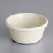 An Acopa bone white smooth melamine ramekin on a gray surface.