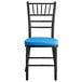 A black Lancaster Table & Seating Chiavari chair with a blue cushion.