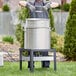 A man wearing an apron and gloves standing in front of a large Backyard Pro seafood boiler.