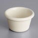 An Acopa bone white melamine ramekin on a gray surface.