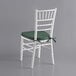 A white Lancaster Table & Seating Chiavari chair with a green cushion.