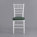 A Lancaster Table & Seating white Chiavari chair with a green cushion.