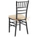 A black Lancaster Table & Seating Chiavari chair with a tan cushion.