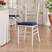 A white wood Chiavari chair with a navy blue cushion.
