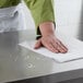 A person cleaning a counter with a Choice Sports Towel.