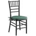 A Lancaster Table & Seating black chiavari chair with green cushion.