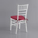 A white Lancaster Table & Seating Chiavari chair with a red cushion.