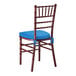 A mahogany wood Chiavari chair with a blue cushion tied to the seat.