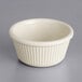 An Acopa Bone White fluted ramekin on a gray surface.