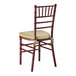 A mahogany wood Chiavari chair with a gold cushion tied to the seat.