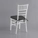 A white Lancaster Table & Seating Chiavari chair with a black cushion.