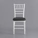 A white Lancaster Table & Seating Chiavari chair with a black cushion.