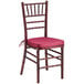 A Lancaster Table & Seating mahogany Chiavari chair with a wine red cushion.