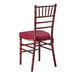 A mahogany wood Chiavari chair with a wine red cushion.