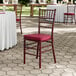 A mahogany wood Chiavari chair with a wine red cushion.