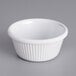 An Acopa white fluted ramekin on a gray surface.